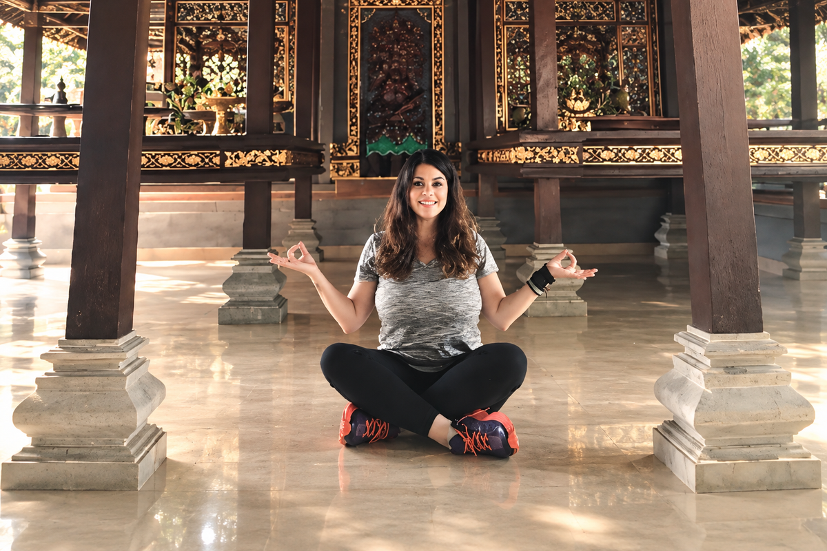 Jacquie seated with open arms in a quiet temple
