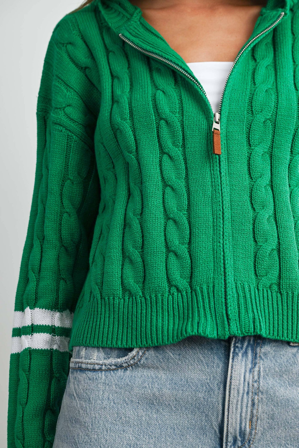 Green cable-knit zip-up hoodie cardigan with ivory sleeve stripes, close-up of zipper and cable knit
