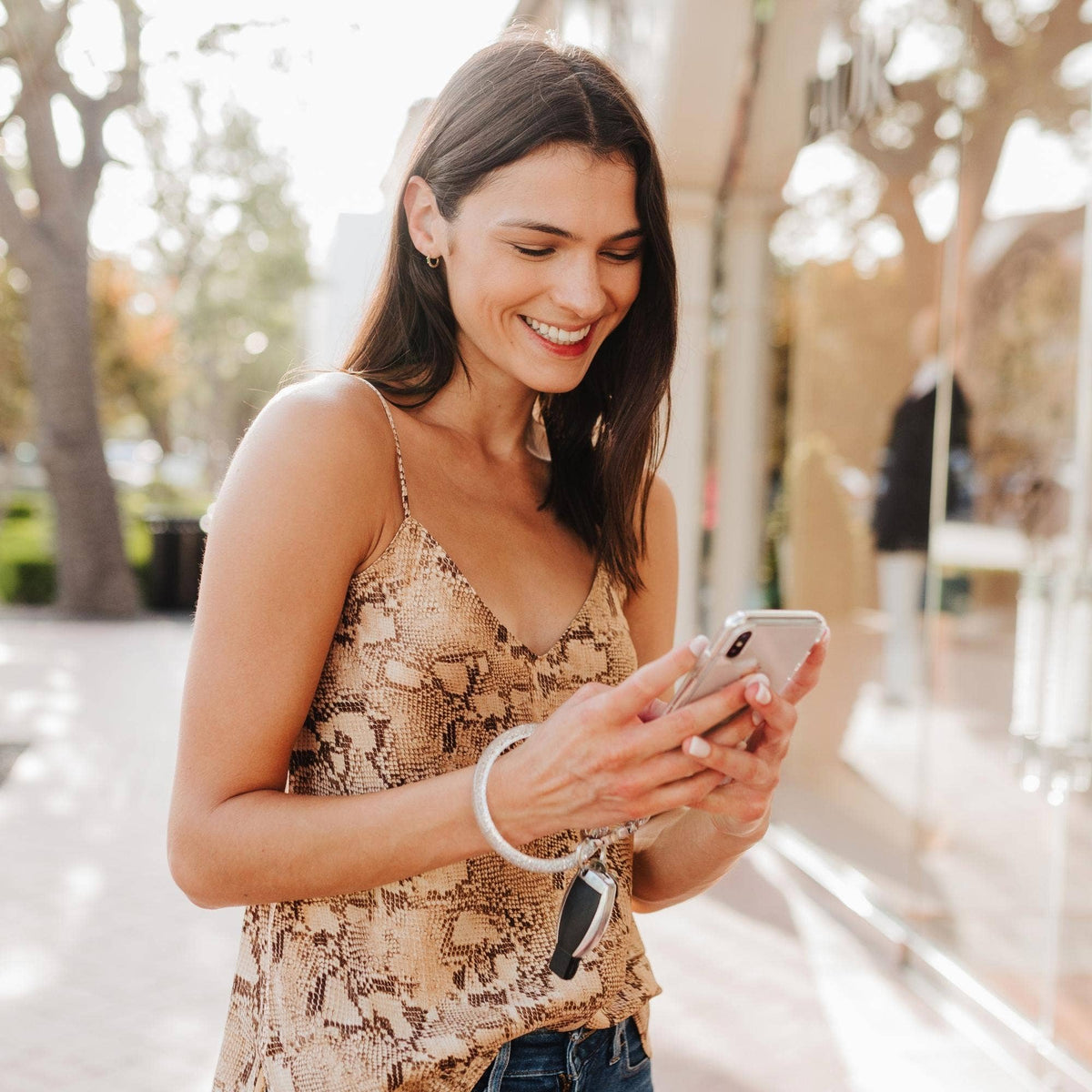 Woman using her phone while carrying keys hands-free on a silver Big O keychain