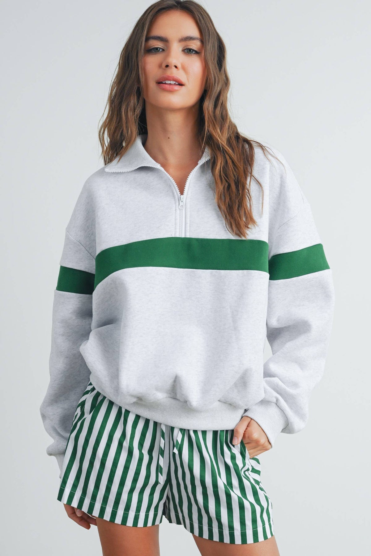 Front view of grey half-zip sweatshirt with green chest and sleeve stripe