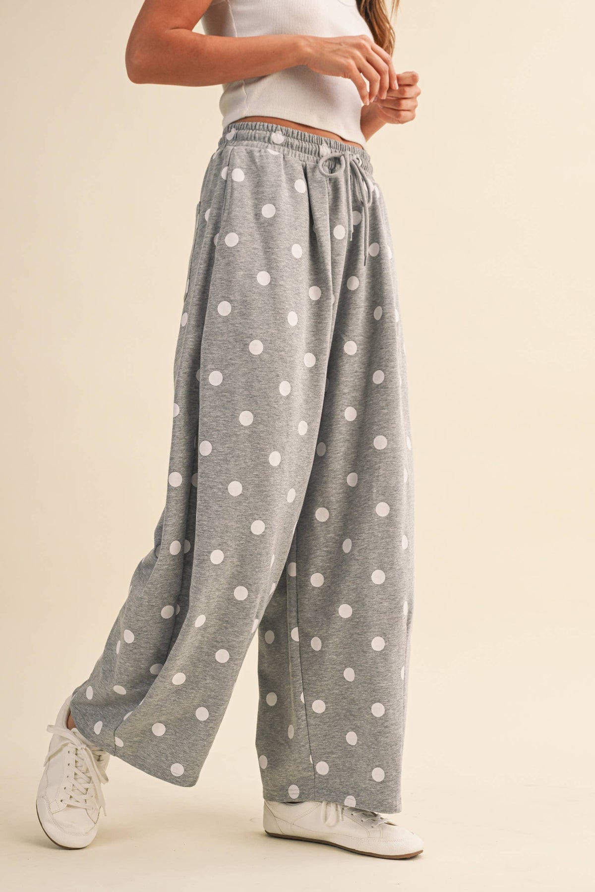 Side movement view of the grey and white polka-dot barrel-leg sweatpants
