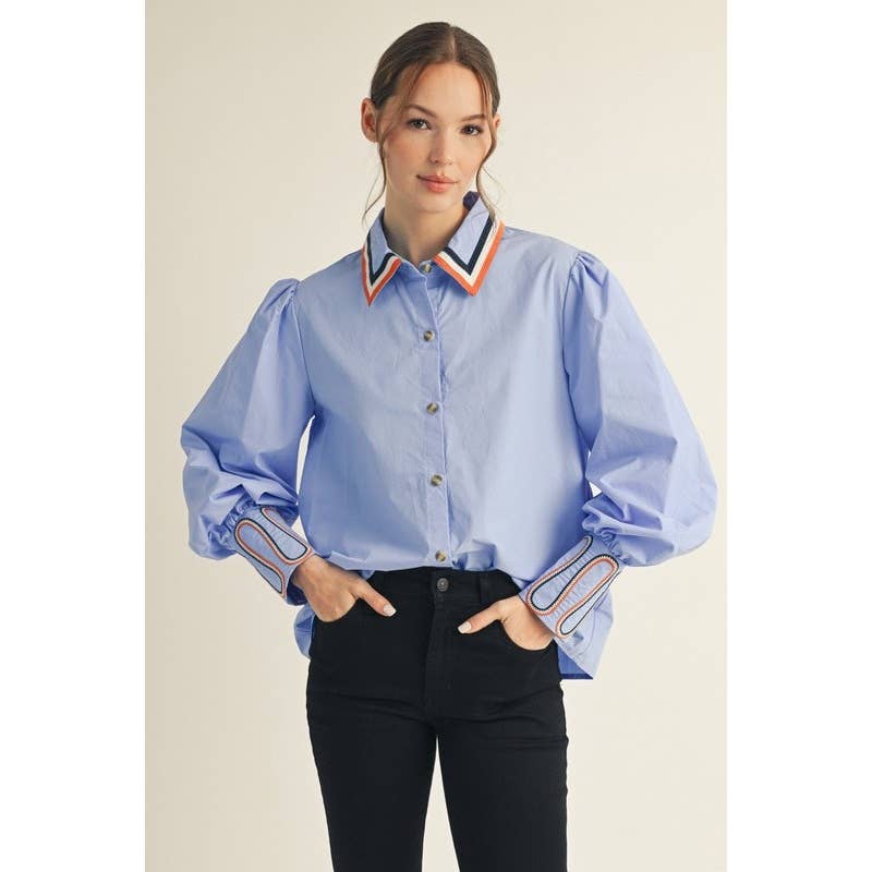 Woman wearing a light blue shirt with colorful collar and cuffs on a beige background