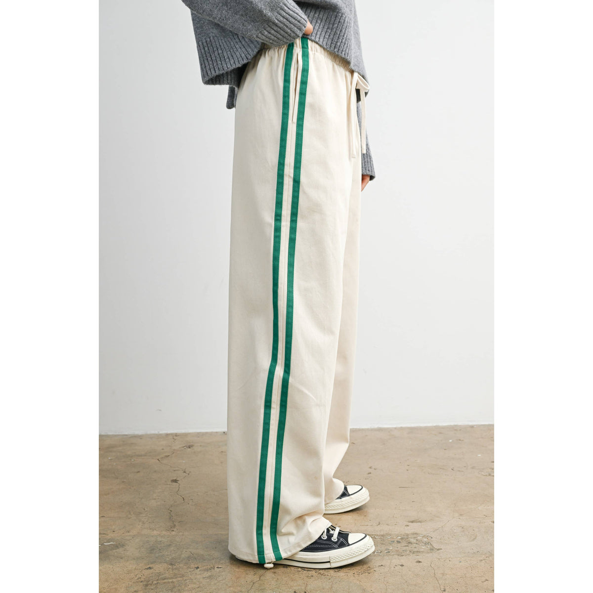 Ivory wide-leg drawstring track pants with green side stripes, side view