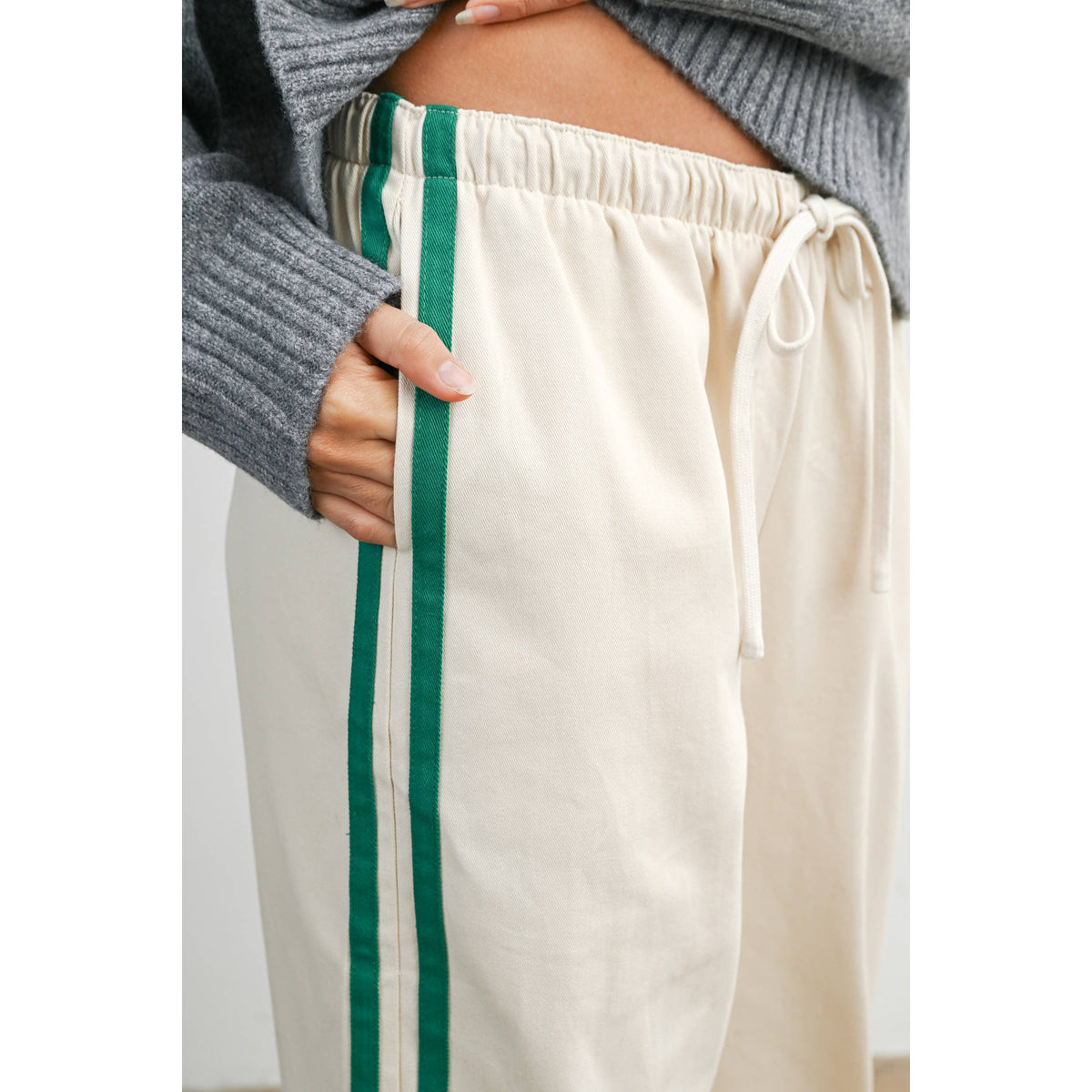 Ivory wide-leg drawstring track pants with green side stripes, close-up of drawstring waist and side stripes