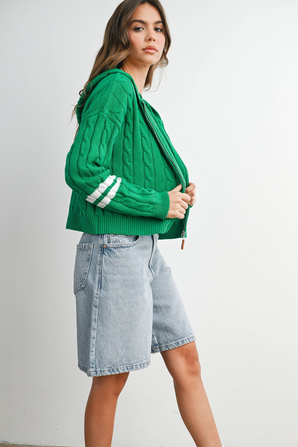Green cable-knit zip-up hoodie cardigan with ivory sleeve stripes, side outfit view