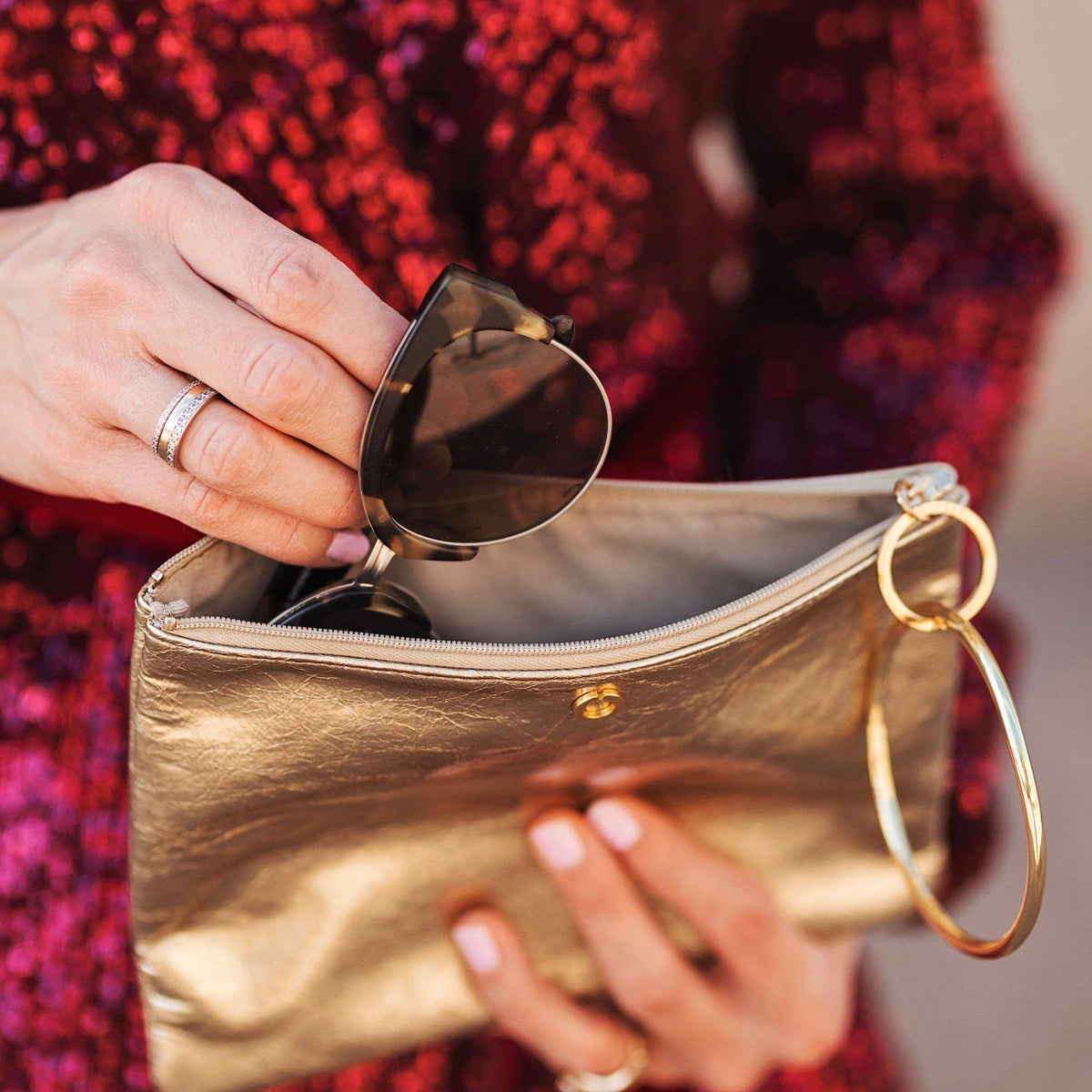 Close view of sunglasses being placed inside the Gold Rush bracelet pouch