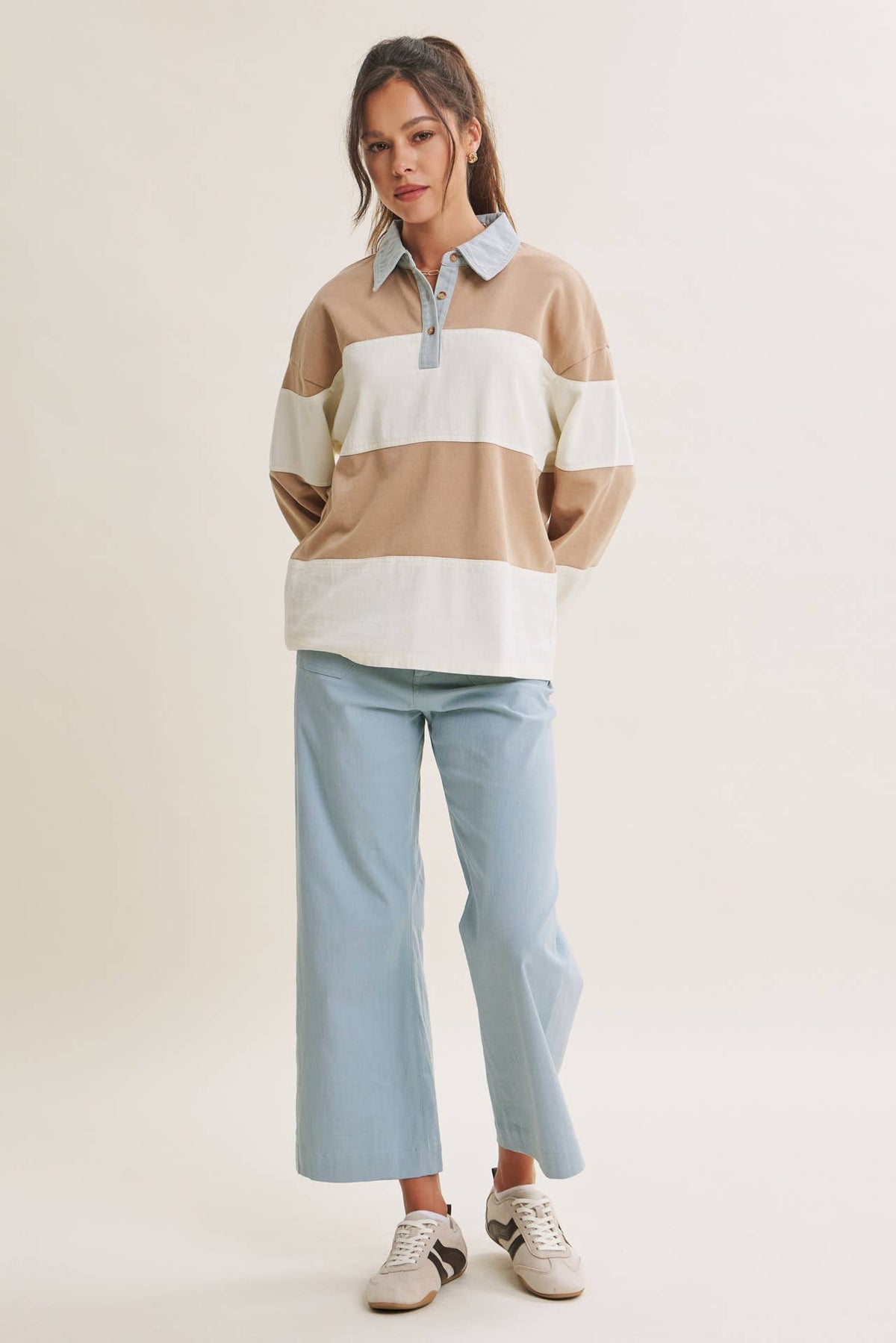 Front view of the latte and cream striped rugby top worn loose over wide-leg jeans.