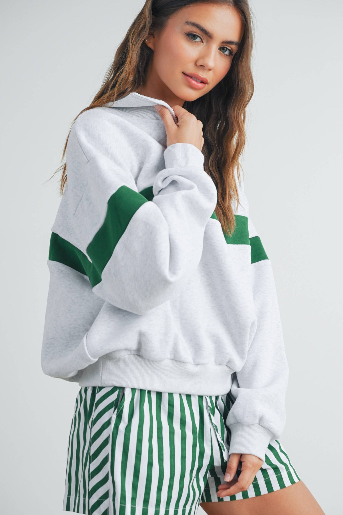 Side view showing green stripe and half-zip collar on grey sweatshirt