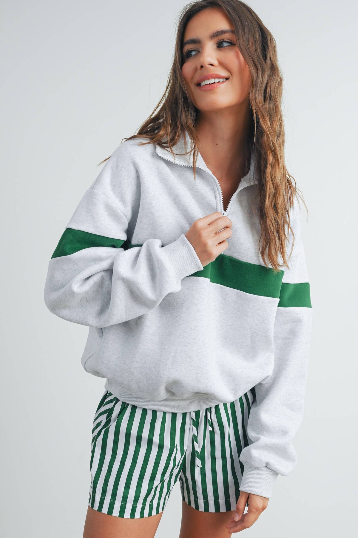 Grey and green half-zip sweatshirt worn with striped shorts