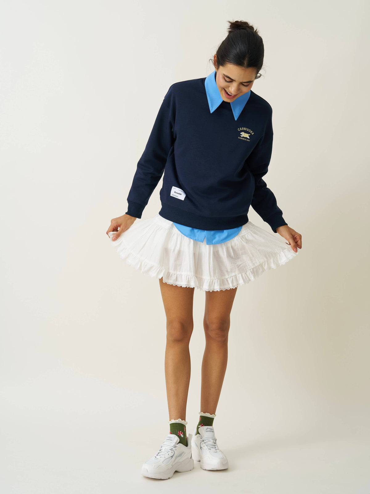 Woman styling olive mushroom ruffle grip socks with a navy pullover and white skirt