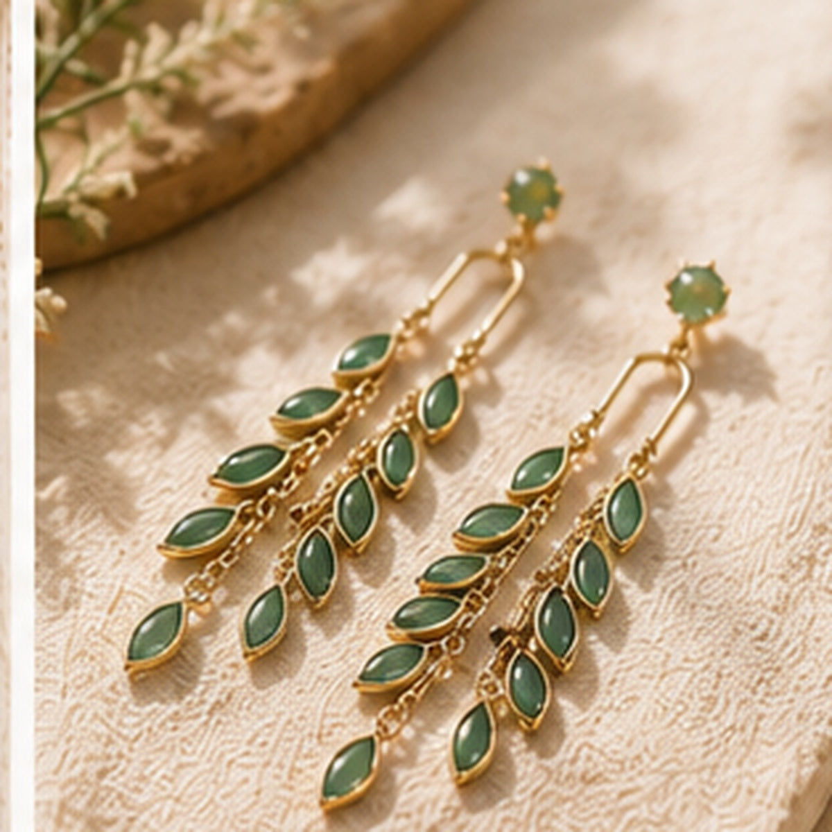 Verdant Cascade green cat-eye stone earrings styled on cream fabric