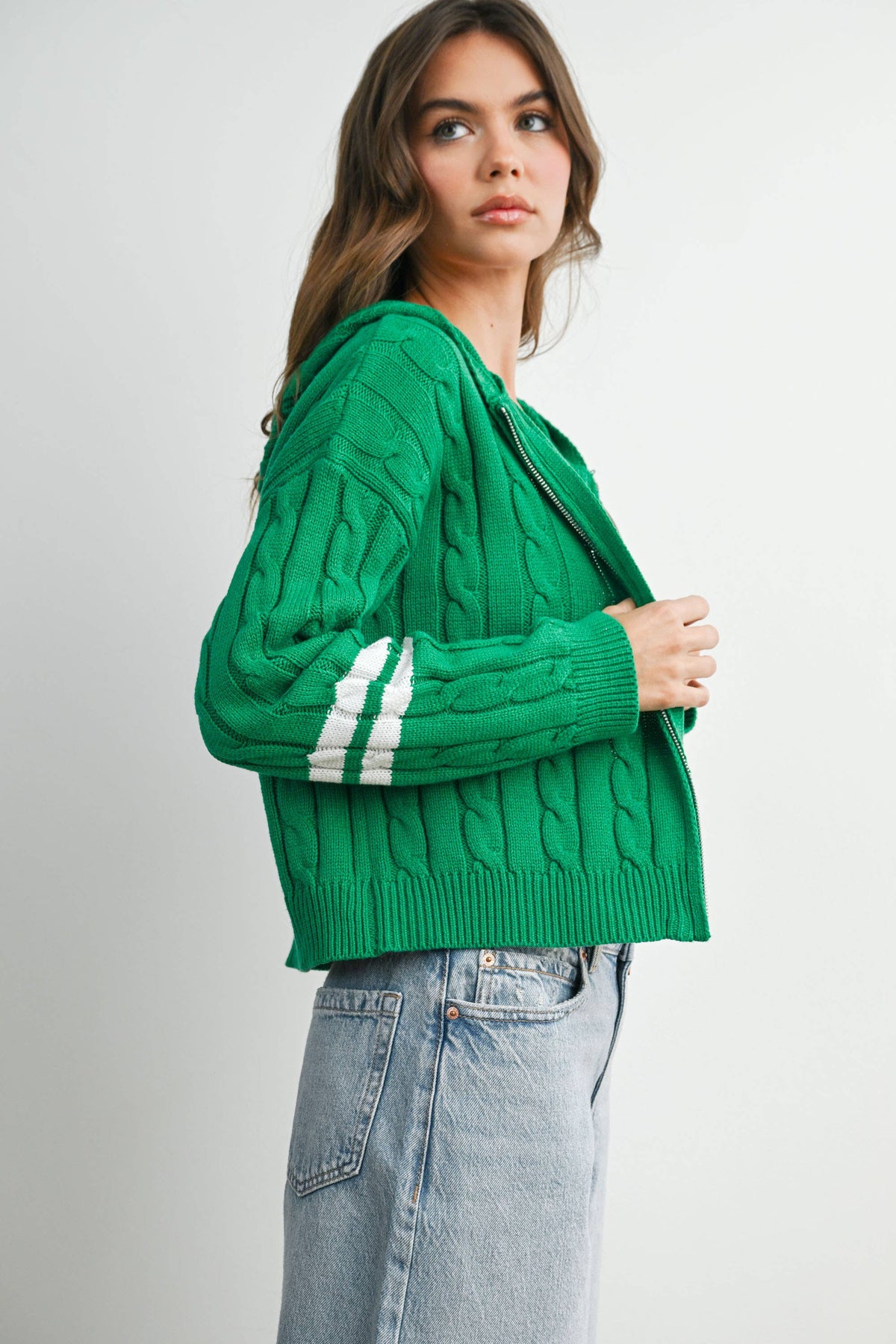 Green cable-knit zip-up hoodie cardigan with ivory sleeve stripes, side view