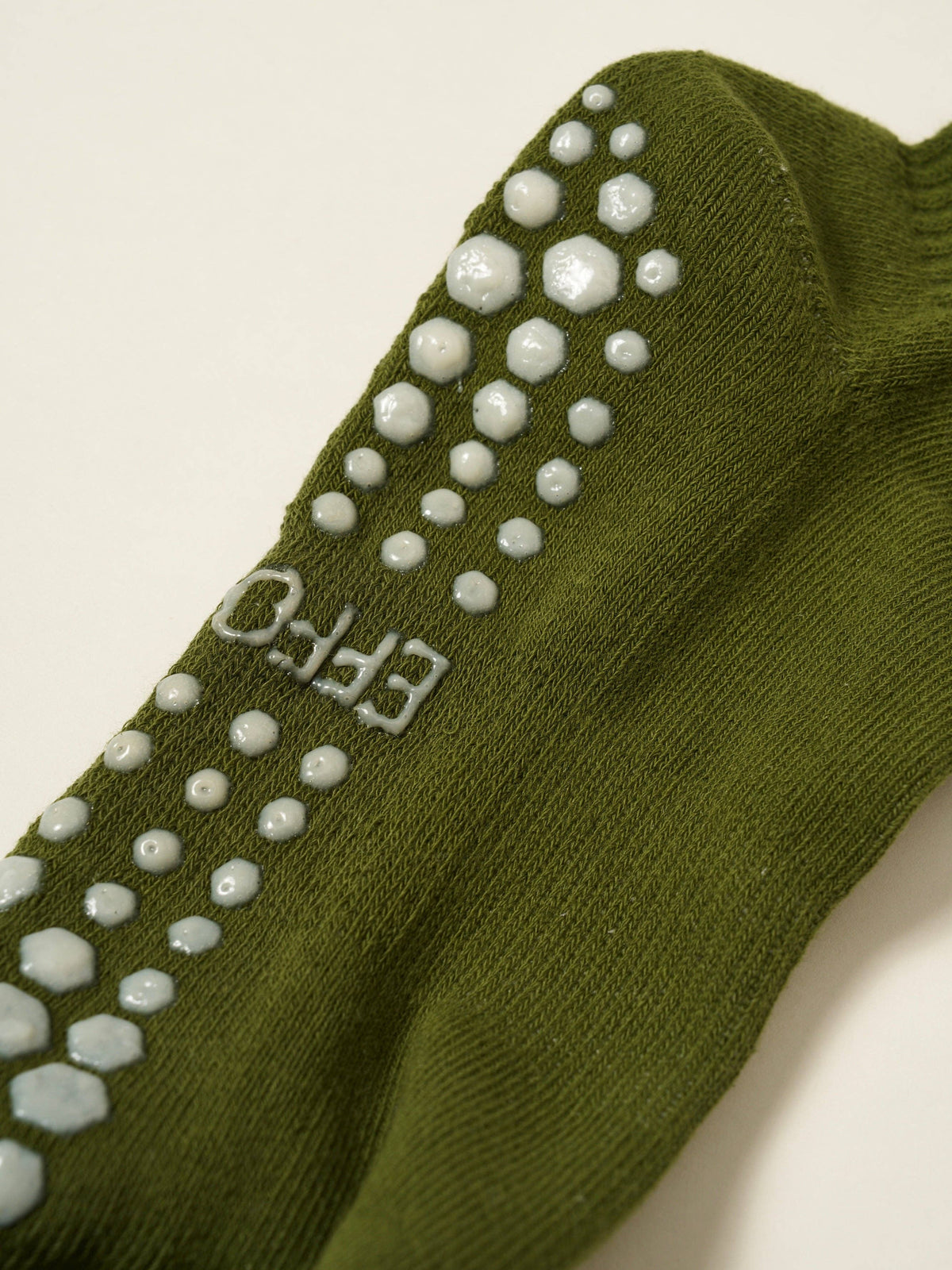 Close-up of the cushioned sole and white grip pattern on the olive sock