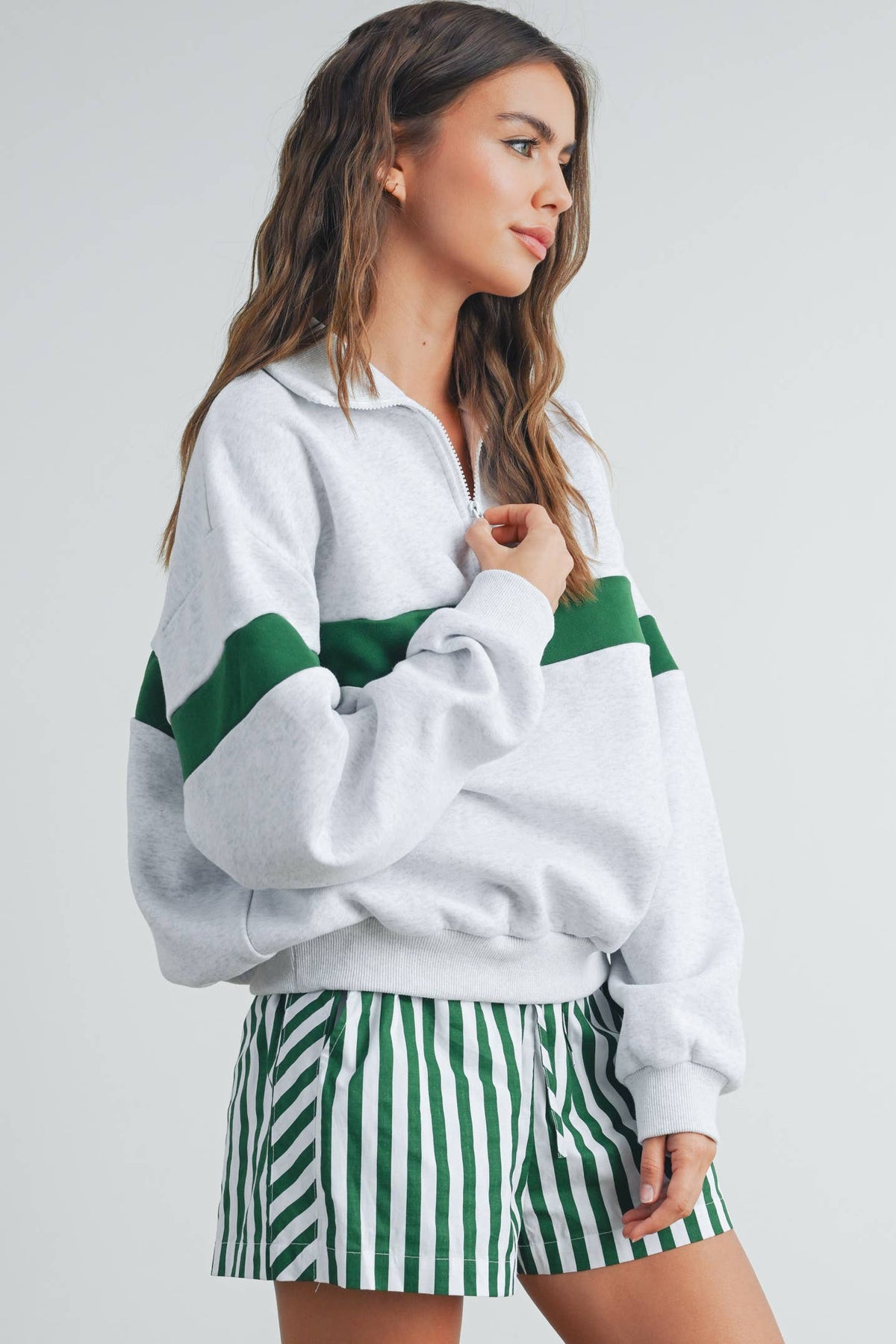 Three-quarter view of grey sweatshirt with green stripe