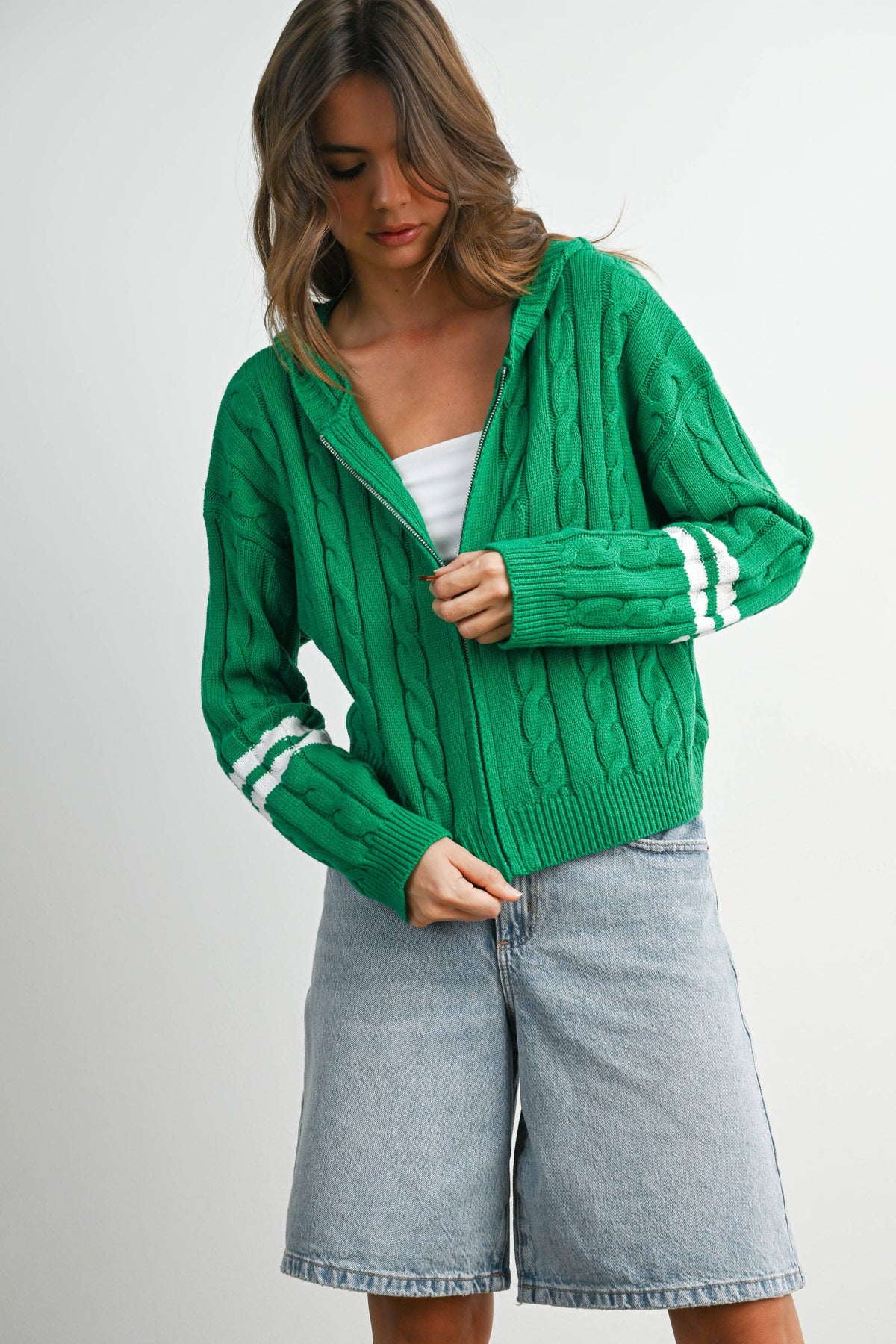 Green cable-knit zip-up hoodie cardigan with ivory sleeve stripes, zipped front view