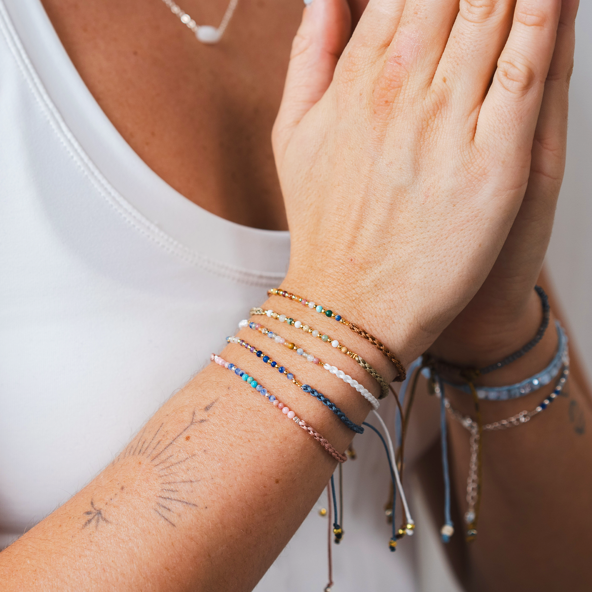 Woman wearing the Om Namaste bracelet in a colorful delicate bracelet stack