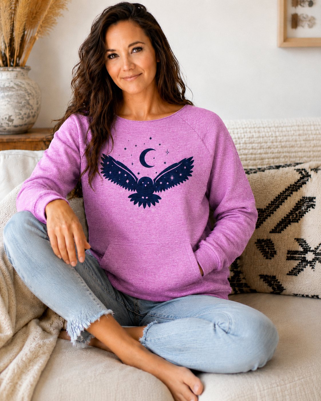 Woman wearing a purple sweater with an owl design, sitting on a couch.