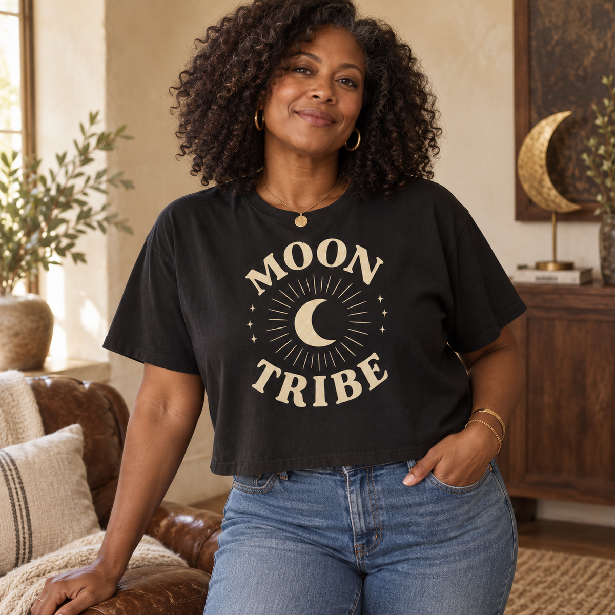 Woman wearing the Black Cozy Moon Tribe cropped boxy tee with high-rise denim in a warm House of Caelo setting