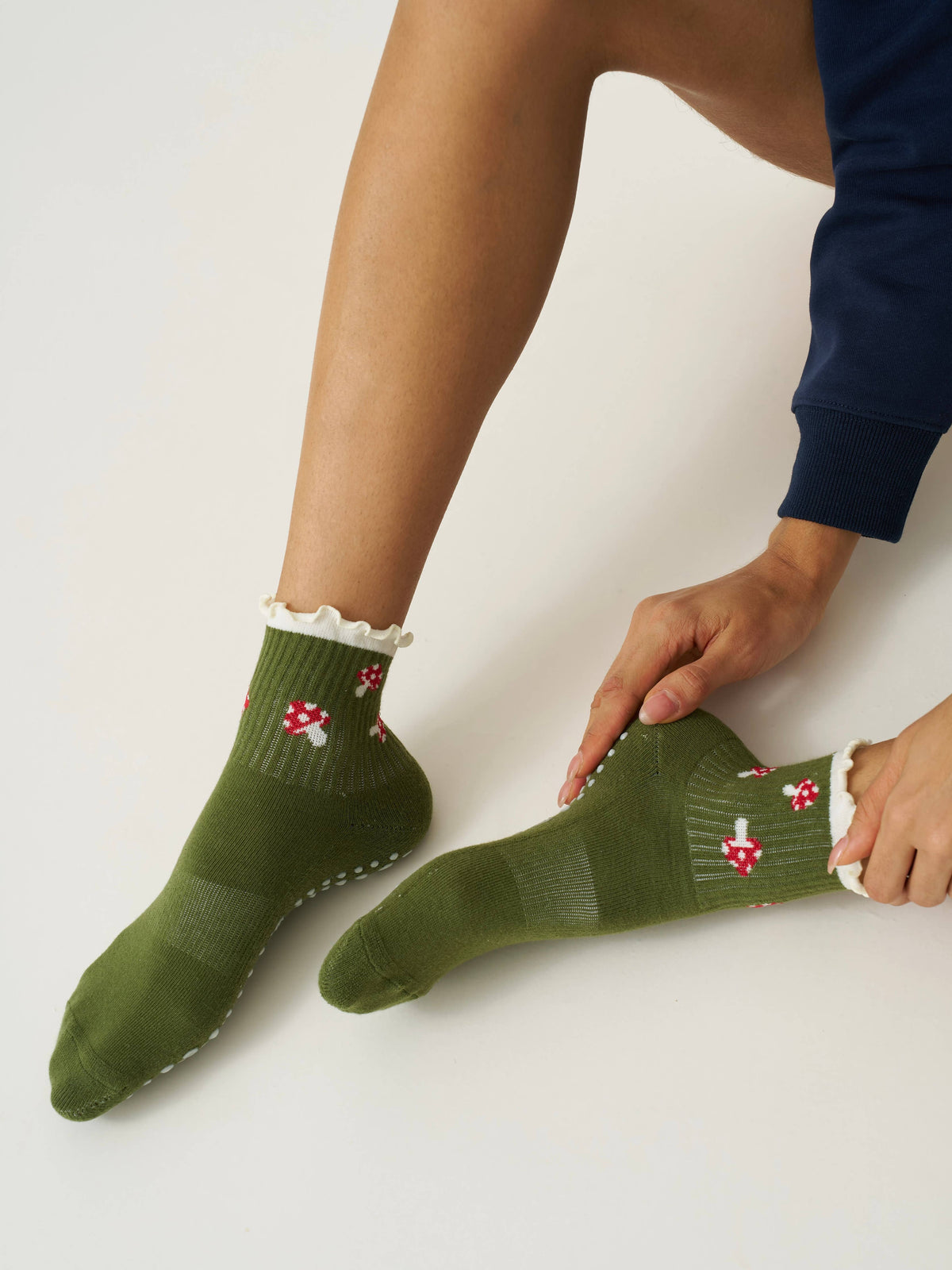 Woman adjusting an olive mushroom ruffle grip sock before movement