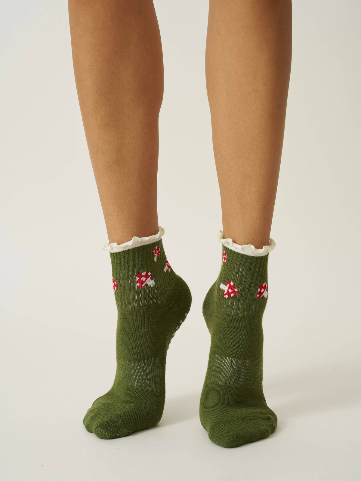 Olive mushroom ruffle grip socks worn against a cream studio background