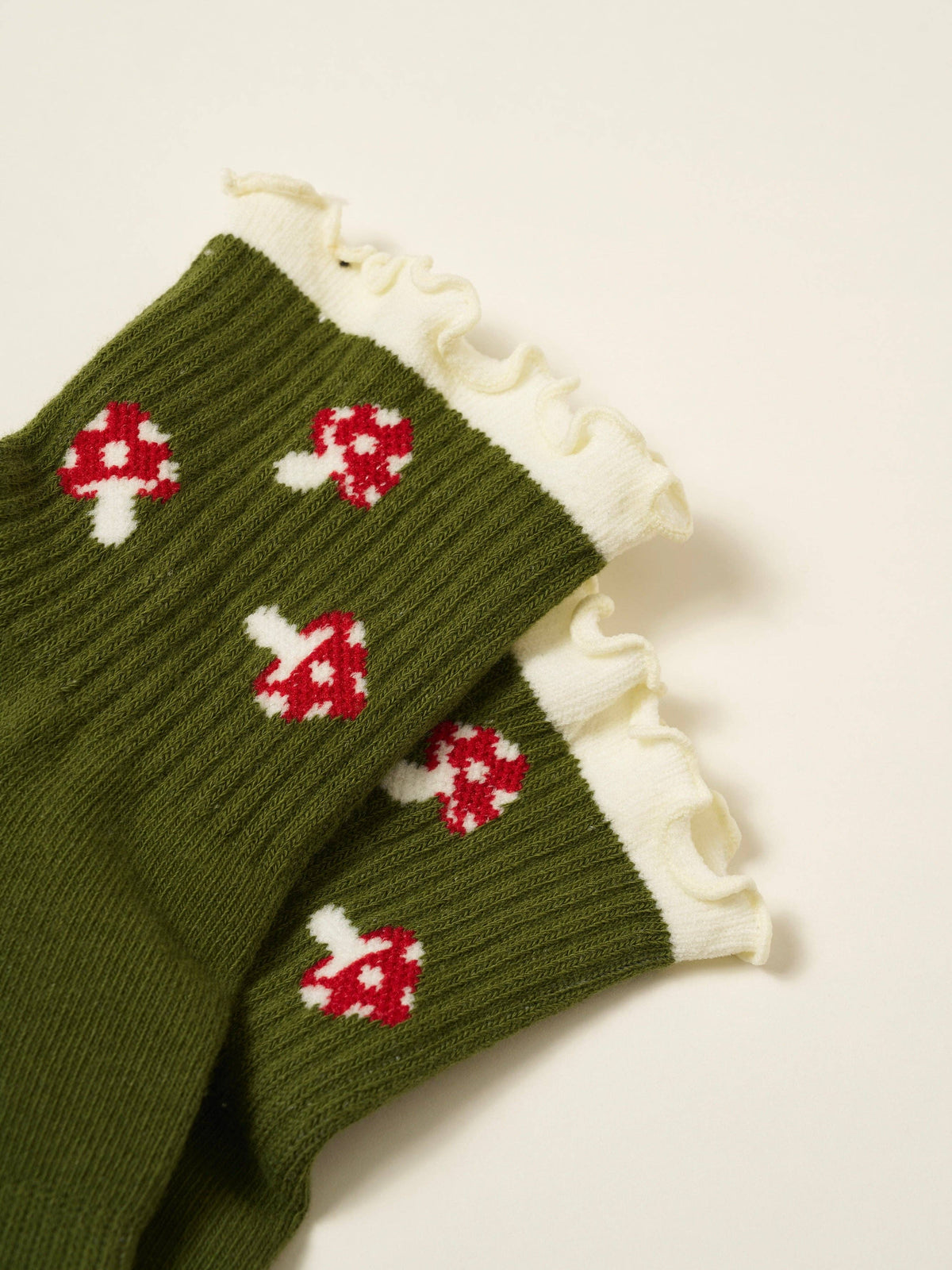 Olive grip socks with red and white mushroom pattern and ivory ruffle cuffs