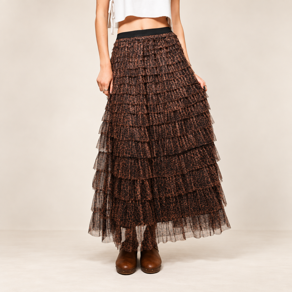 Front view of the leopard tiered ruffle maxi skirt with black elastic waistband, photographed against a warm ivory background