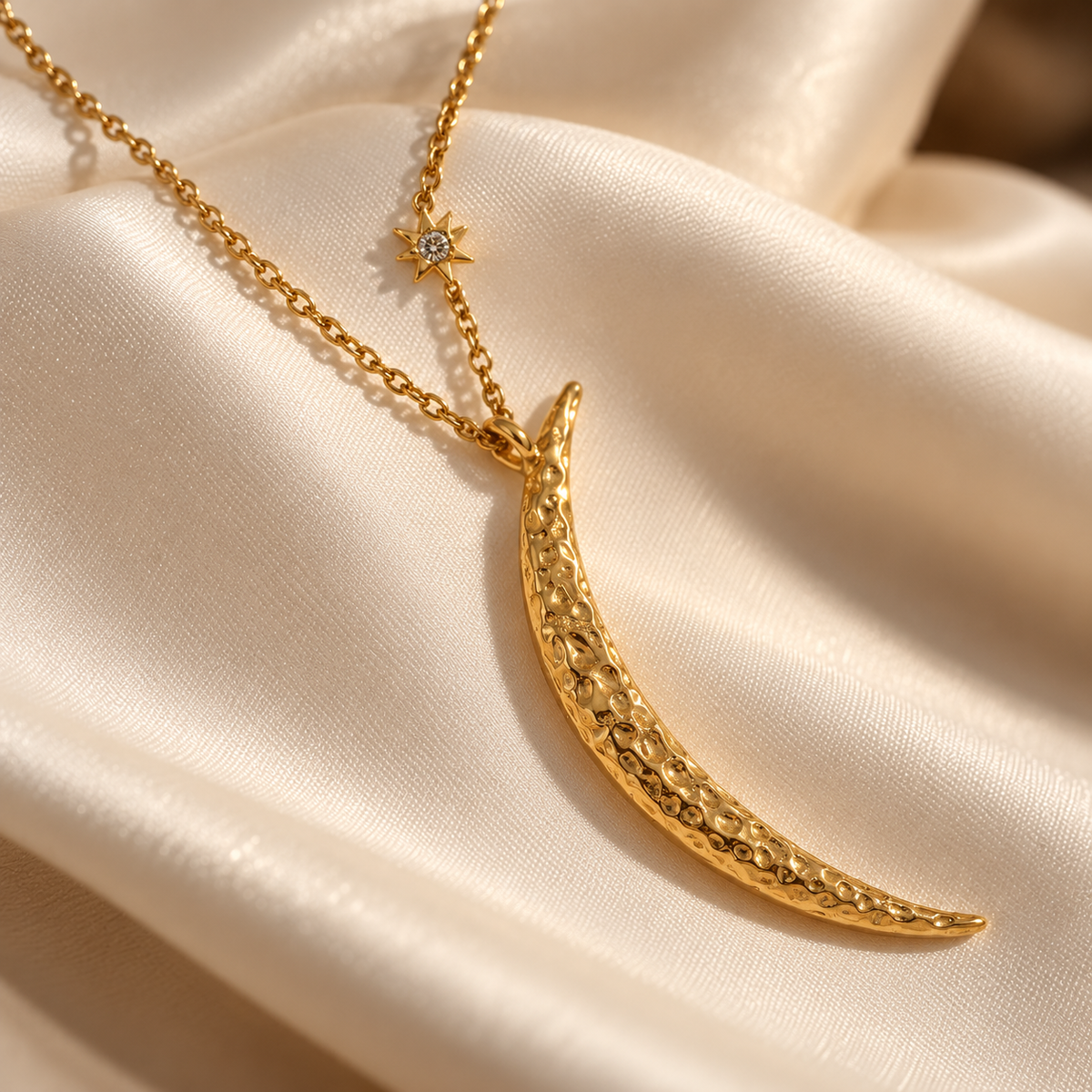 Close detail of the Luna & Light crescent moon necklace, highlighting its textured gold finish and starburst accent on ivory silk.