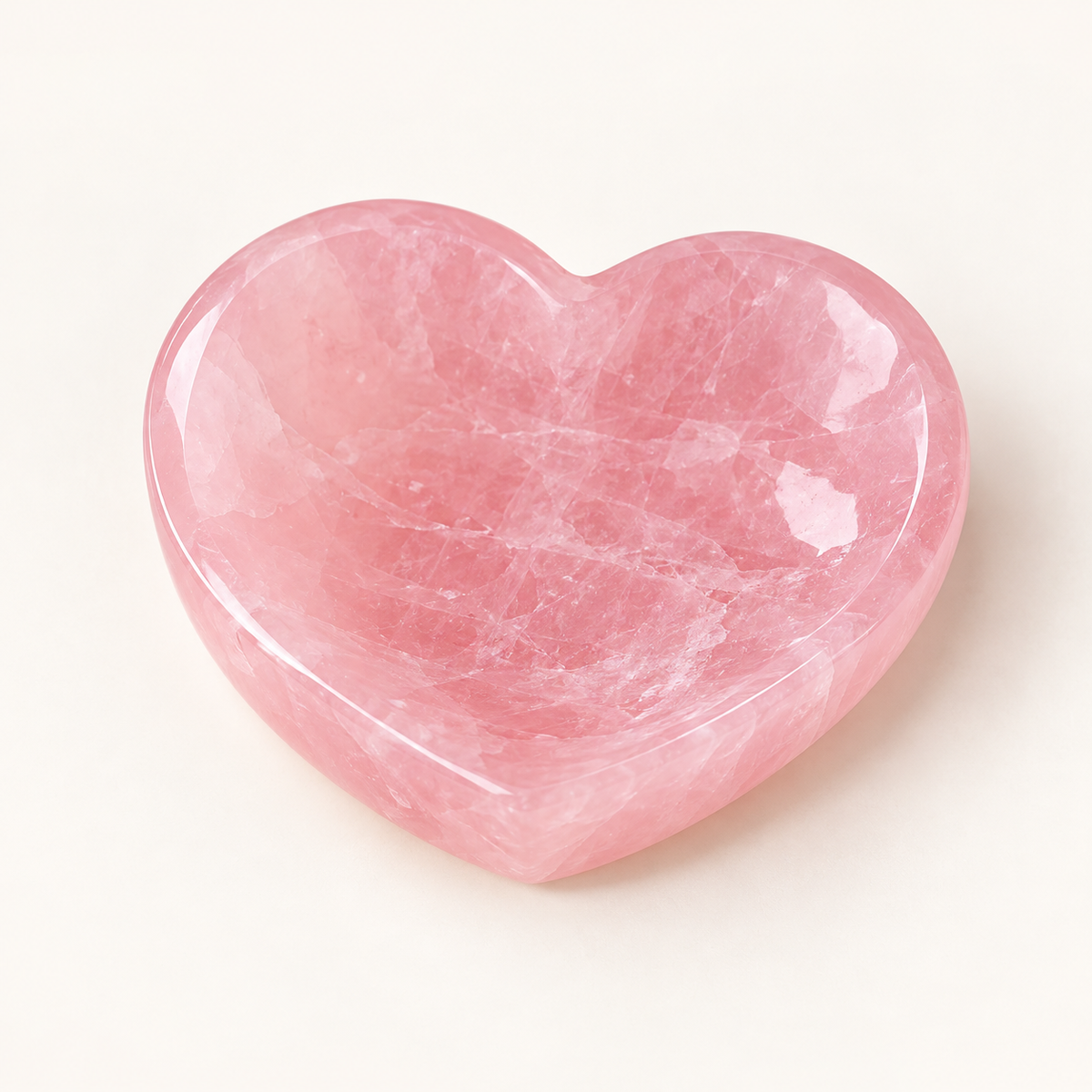 Petite polished rose quartz heart-shaped trinket bowl with natural white veining on an ivory background