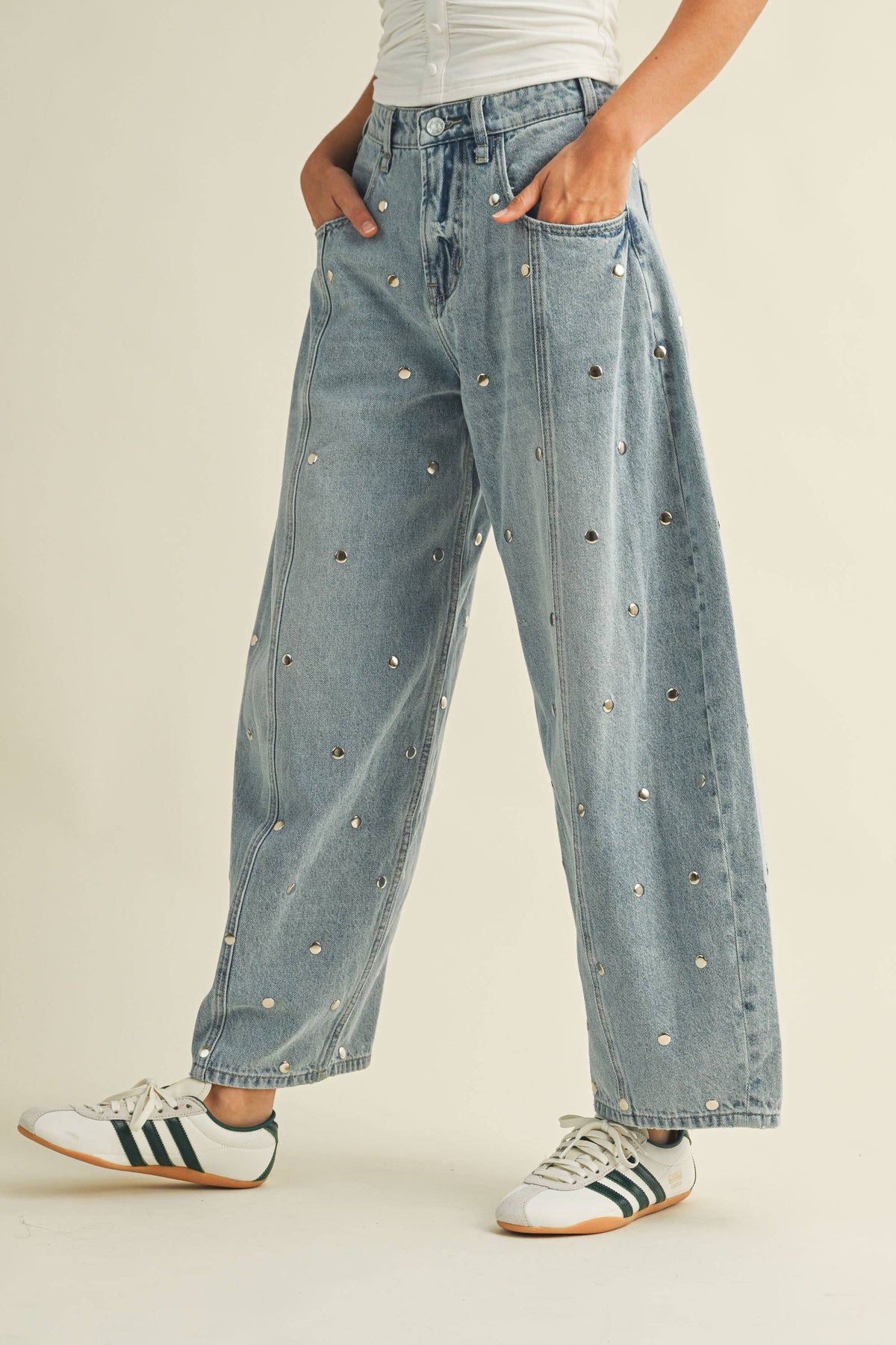 Close-up view of the light denim wash and stud details on barrel leg jeans